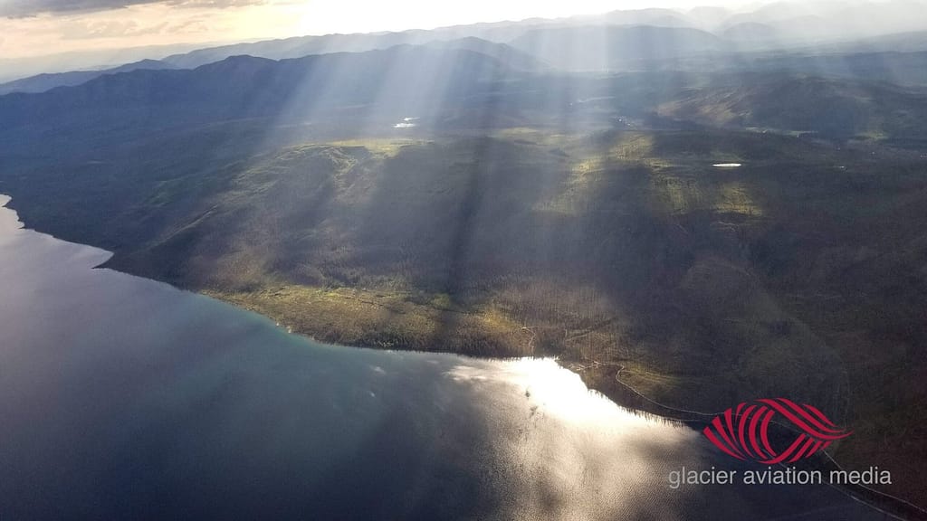 Lake McDonald with dramatic sun rays breaking through clouds, aerial view