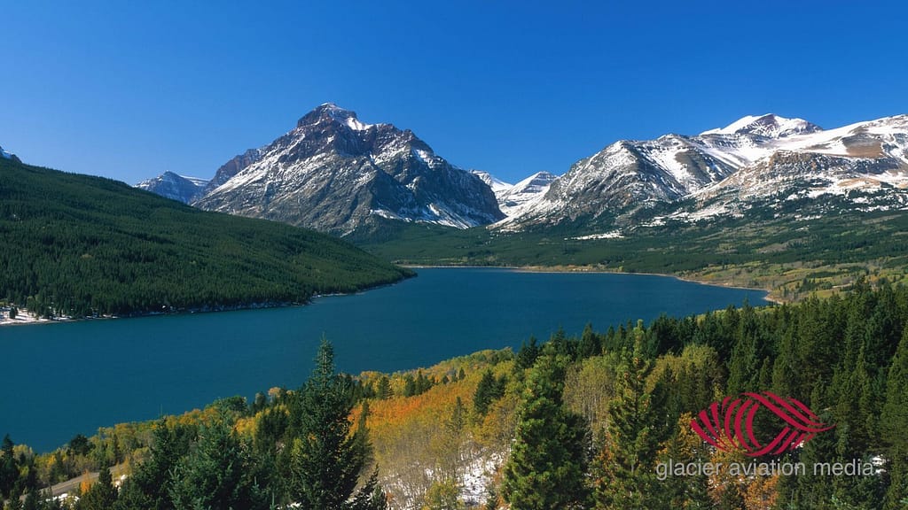 Two Medicine Lake in autumn colors with snow-capped peaks, aerial Montana