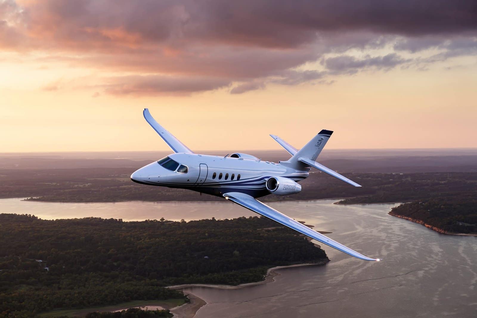 Cessna Latitude Jet in flight with dramatic sunset background.